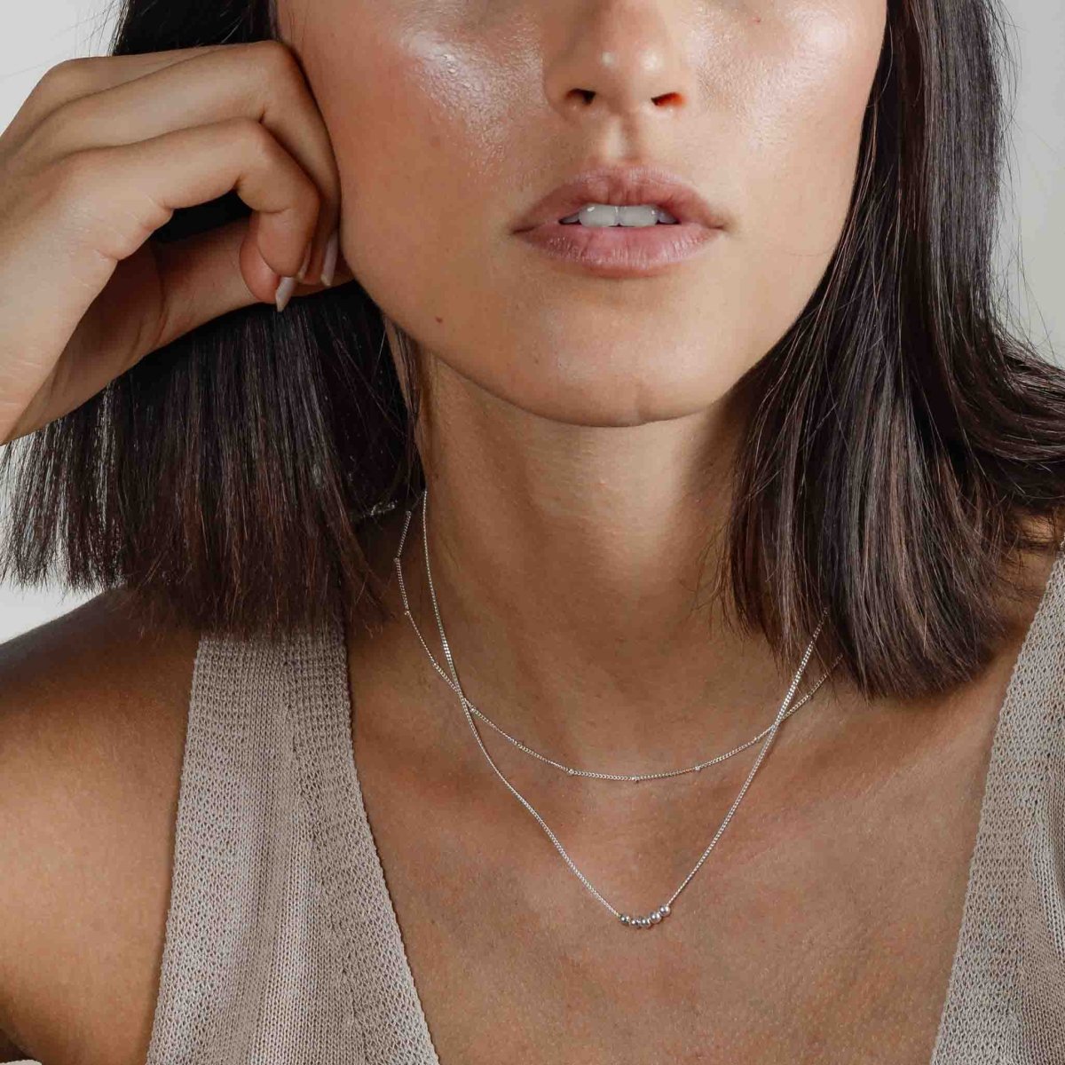 Am Hals des Models hängt eine kurze 925 Silberkette mit fünf aufgezogenen kleinen Silberperlen in der Mitte.