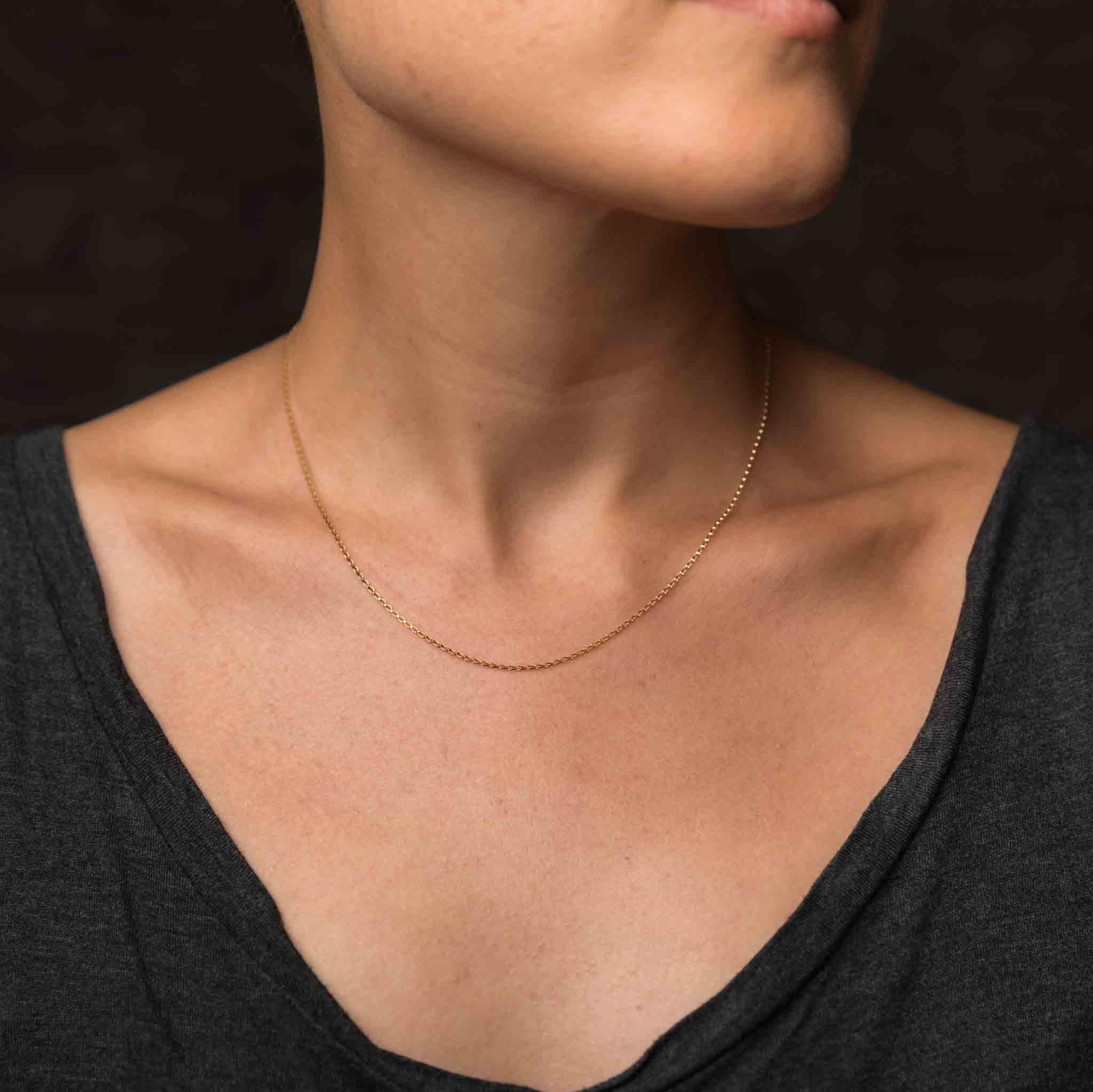 Am Hals des Models hängt eine kurze und zierliche Goldkette aus Goldfill.