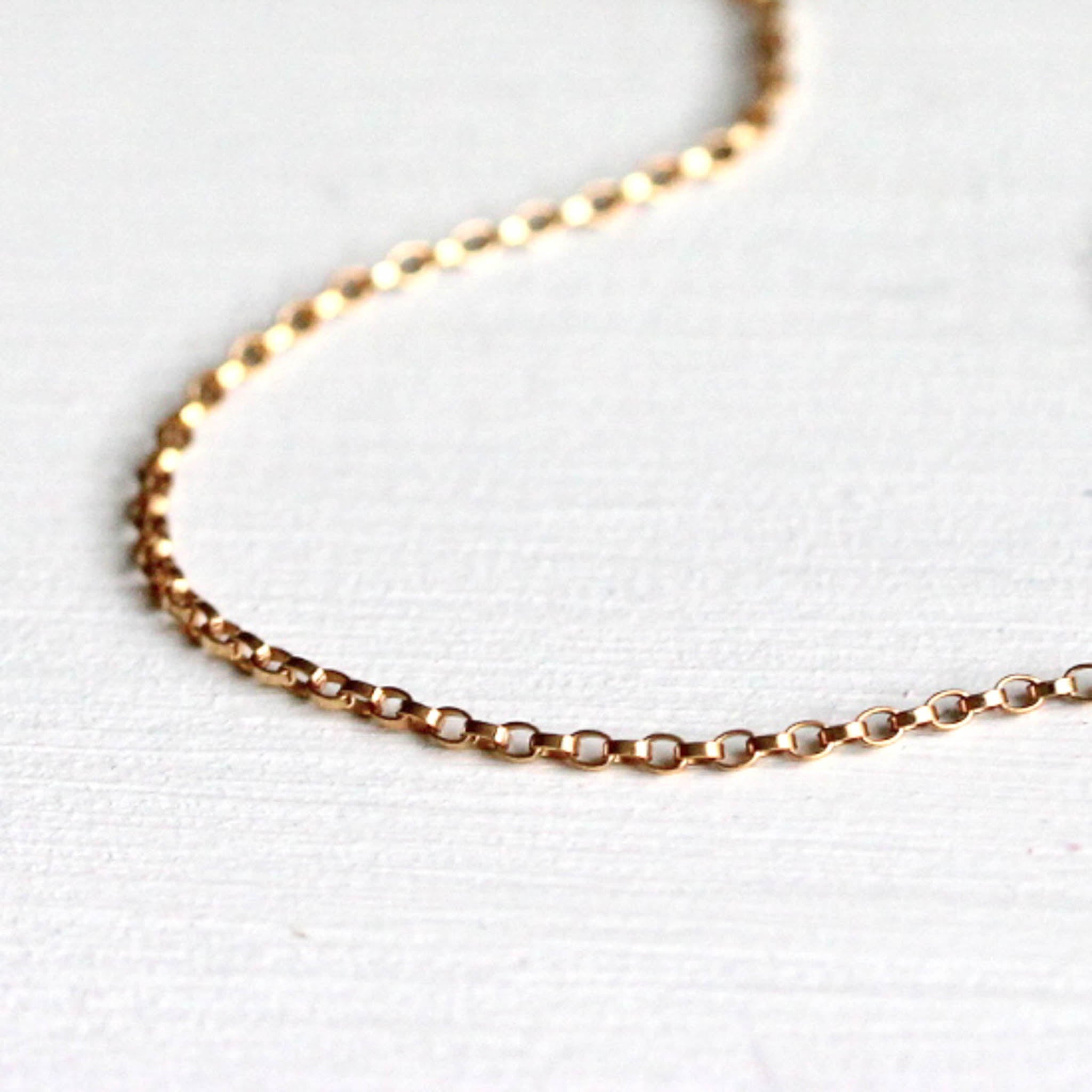 Detailansicht der Kettenglieder einer feinen Goldkette auf weißem Hintergrund.