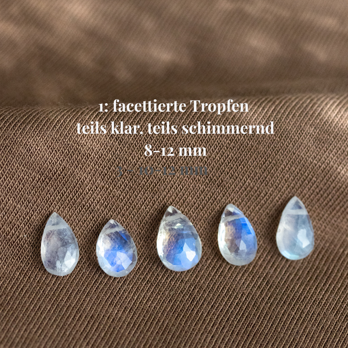 Fünf Mondstein-Tropfen auf Stoff ausgelegt. Beschriftung mit Hinweisen zu Maßen und Qualität.