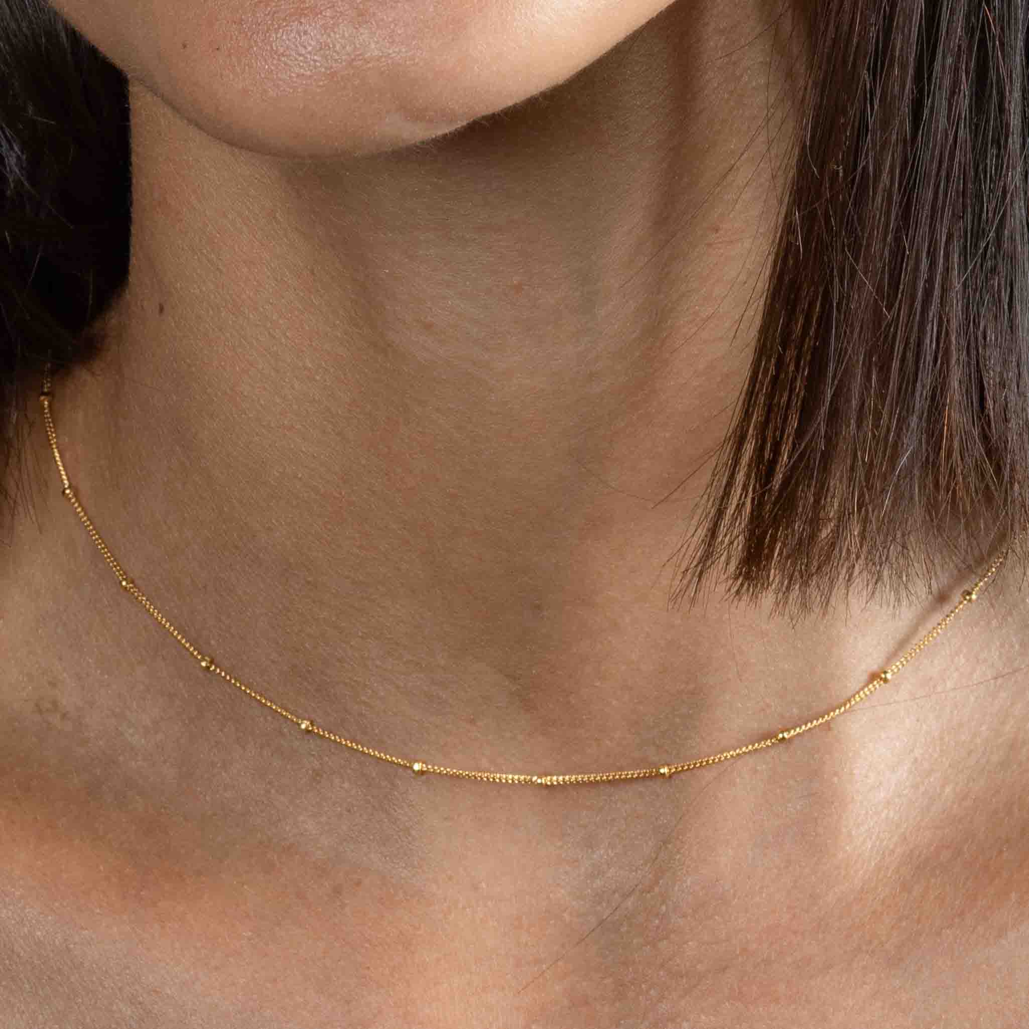 Kurze, goldene Satellitenkette am Hals des Models