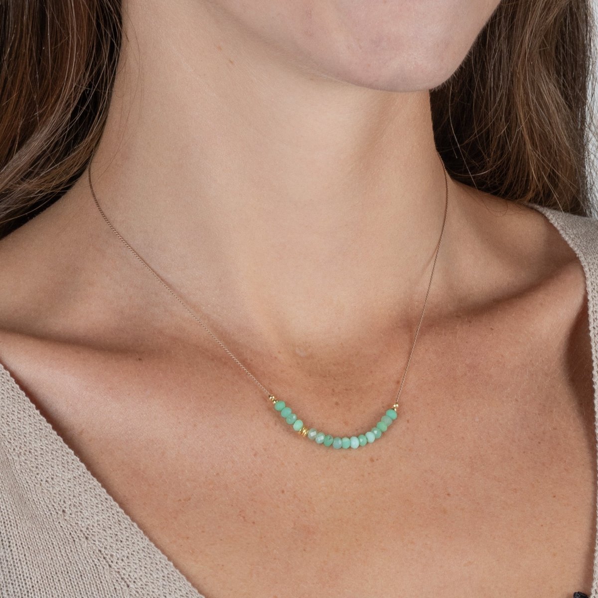 Am Hals des Models hängt eine feine Seidenkette mit einer Reihe grüner Chrysopras-Rondelle und goldenen Akzenten in der Mitte.