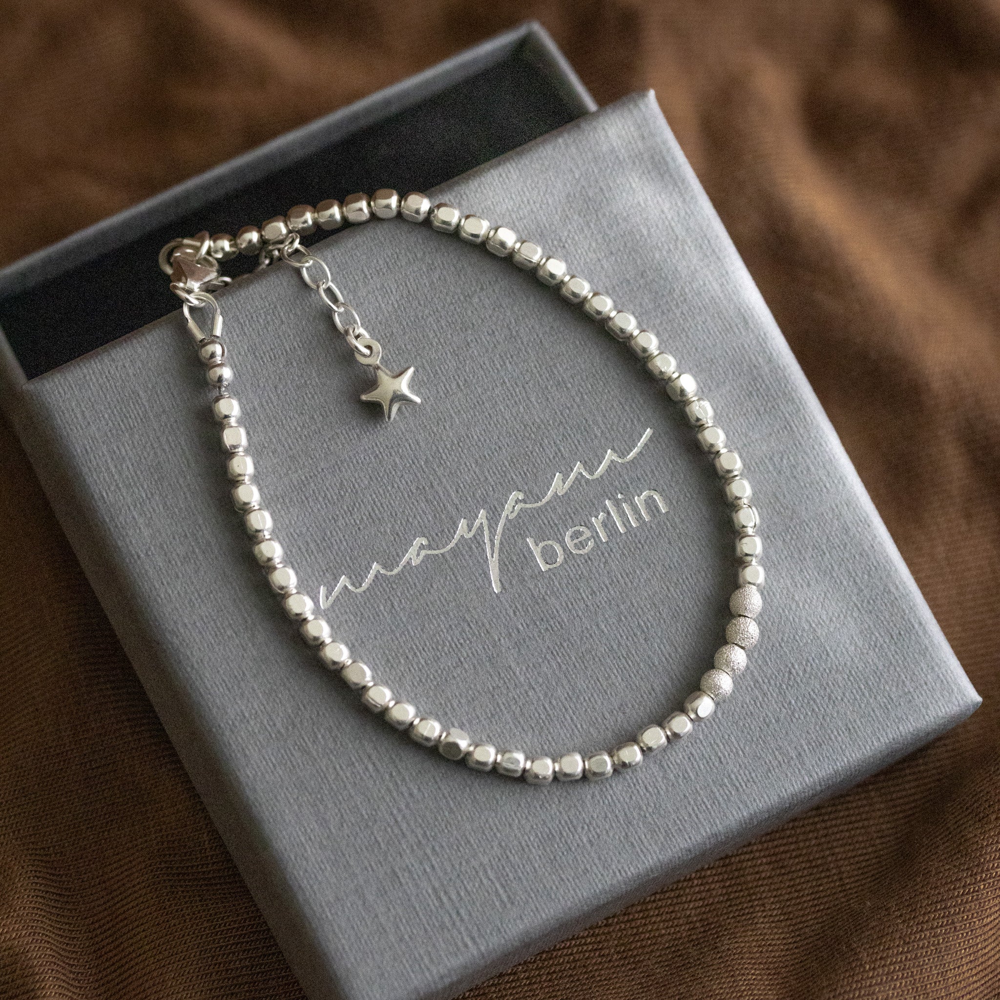 925 Silber Würfel-Armband mit gefrosteten Perlen in der Mitte auf Schmucketui ausgelegt.