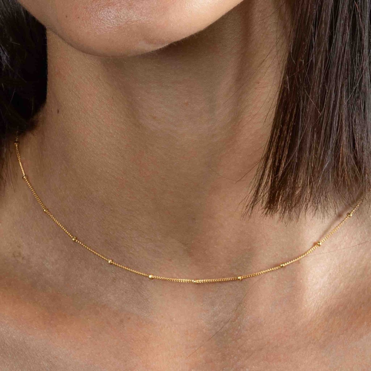 Kurze, goldene Satellitenkette am Hals des Models
