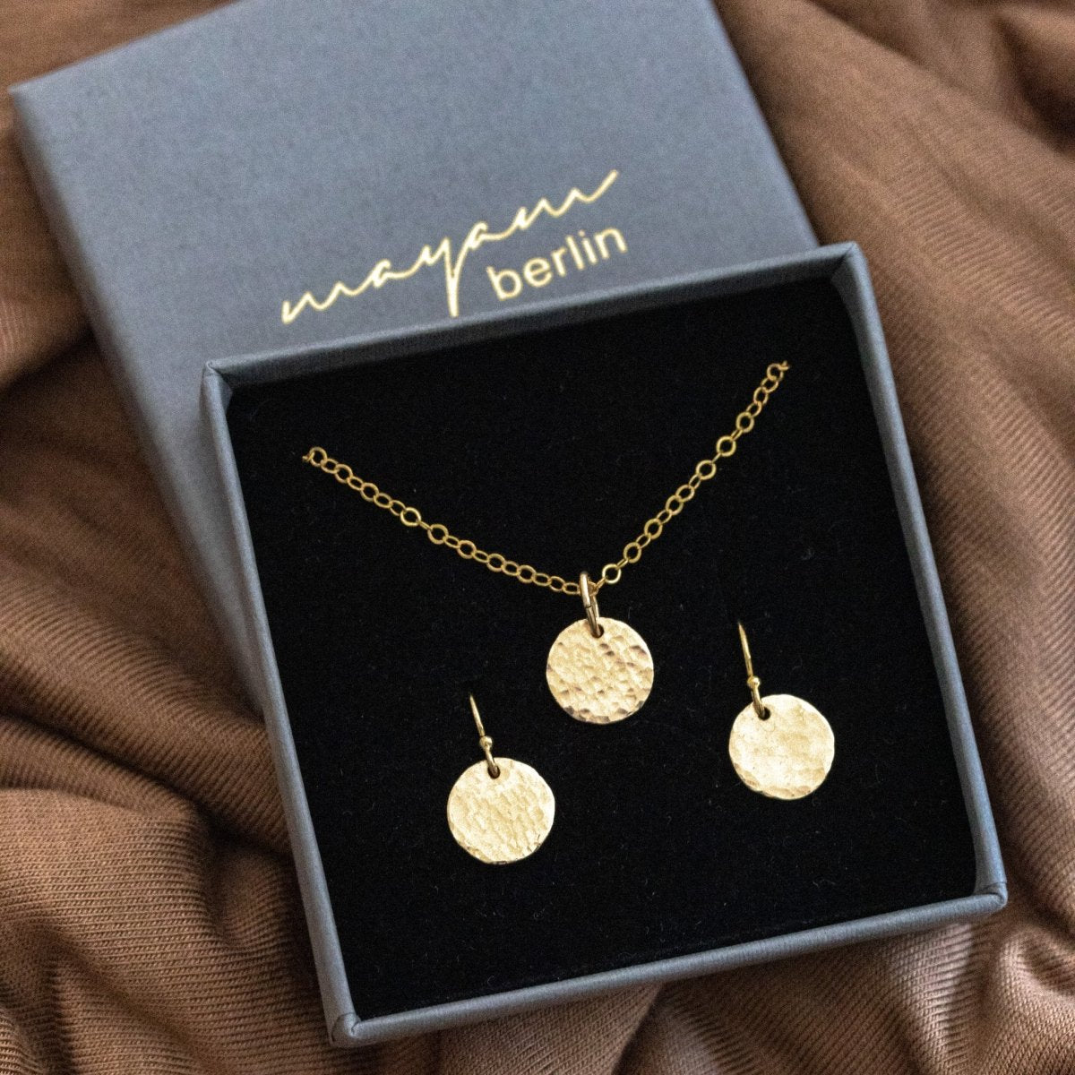 Feine Goldkette mit gehämmertem Plättchen und passende Ohrringe im Mayam Berlin Schmuck-Karton, fertig zum Verschenken.