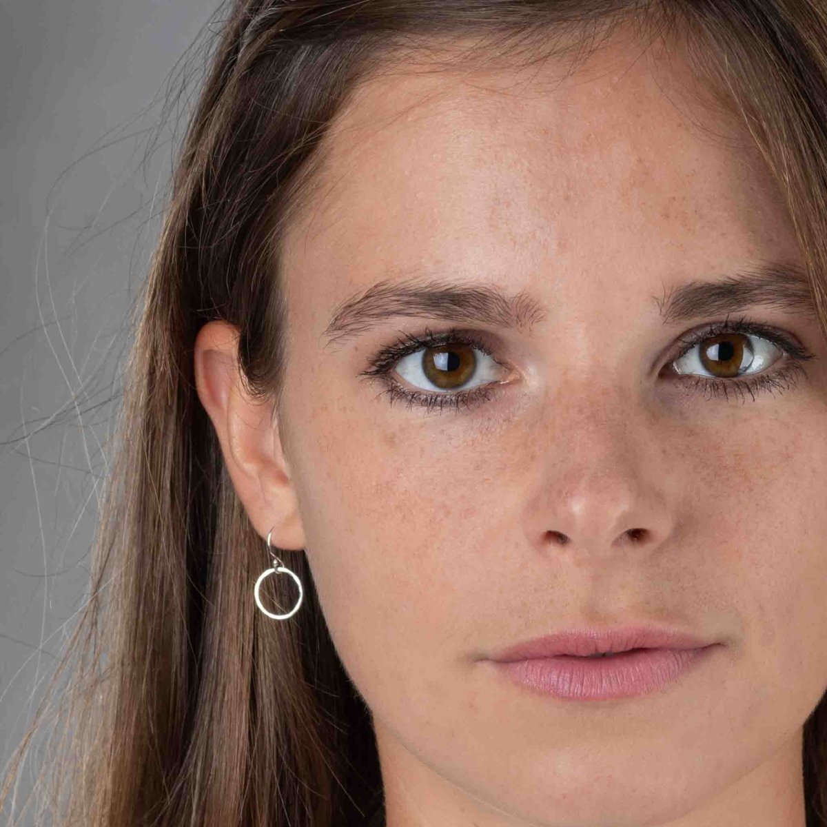 Am Ohr des Models hängt ein kleiner, gehämmerter Ohrring aus Sterling Silber.