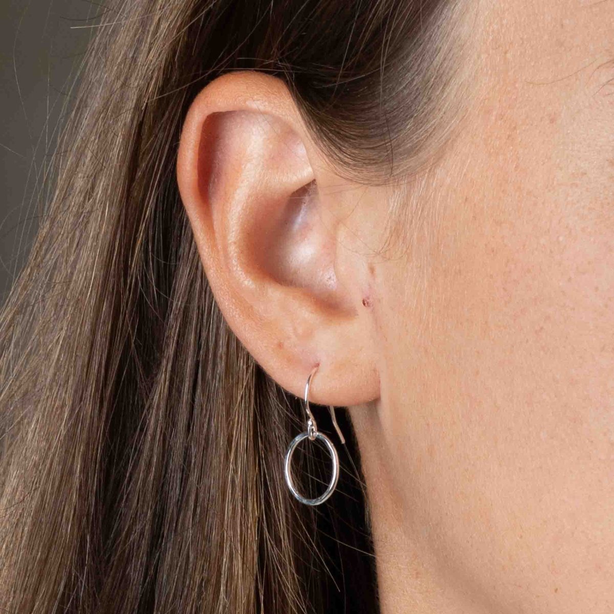 Am Ohr des Models hängt ein kleiner, gehämmerter Ohrring aus Sterling Silber.