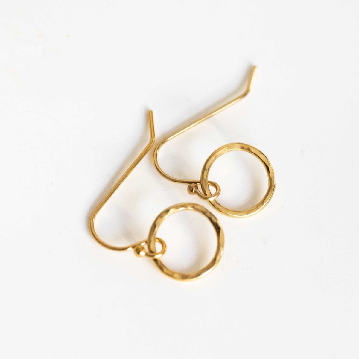 Ein Paar goldener Ohrringe von Mayam Berlin mit Ohrhaken, an denen jeweils ein offener Ring hängt, auf weißem Hintergrund