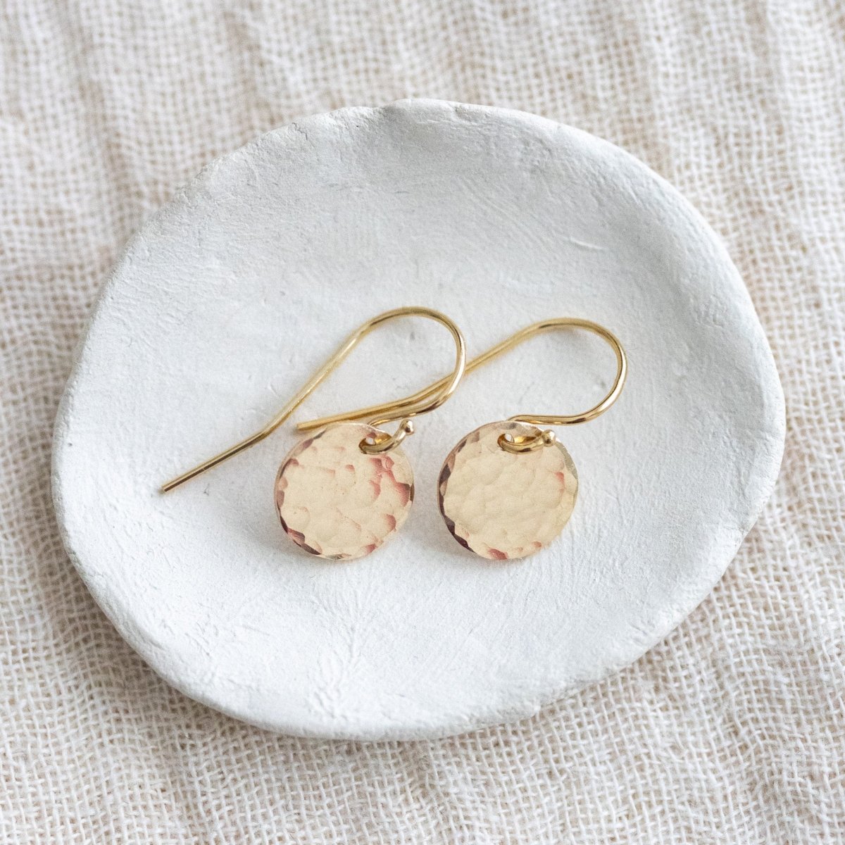 Gold-Ohrringe mit gehämmertem Plättchen, ausgelegt mit Ohrhaken.