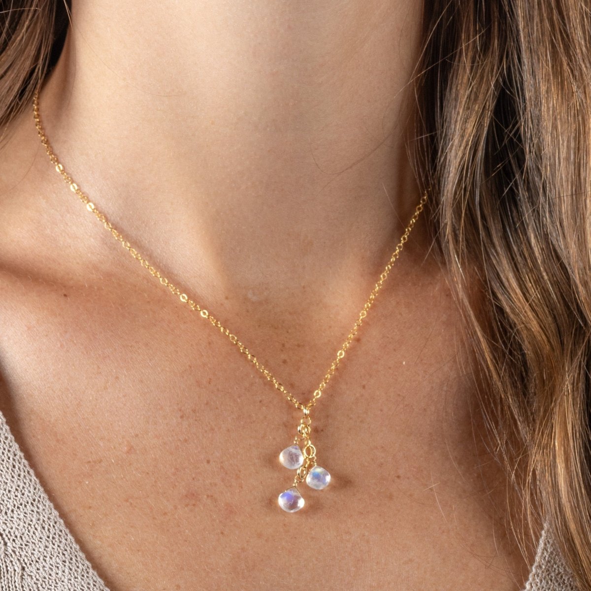 Eine feine Goldkette mit drei untereinander hängenden Mondsteintropfen hängt am Hals des Models.
