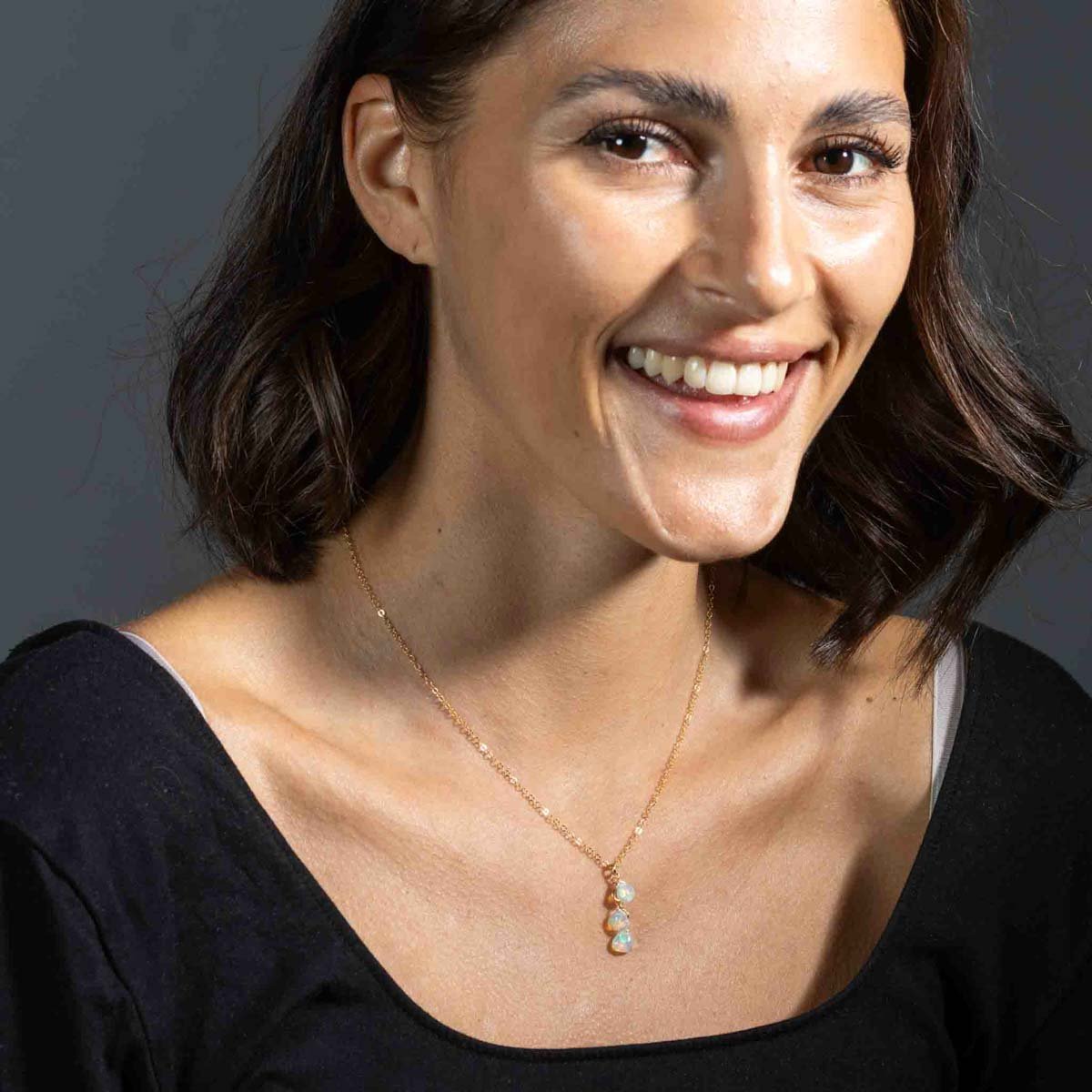 Am Hals des Models hängt eine zarte Goldkette mit drei Opal-Anhängern.
