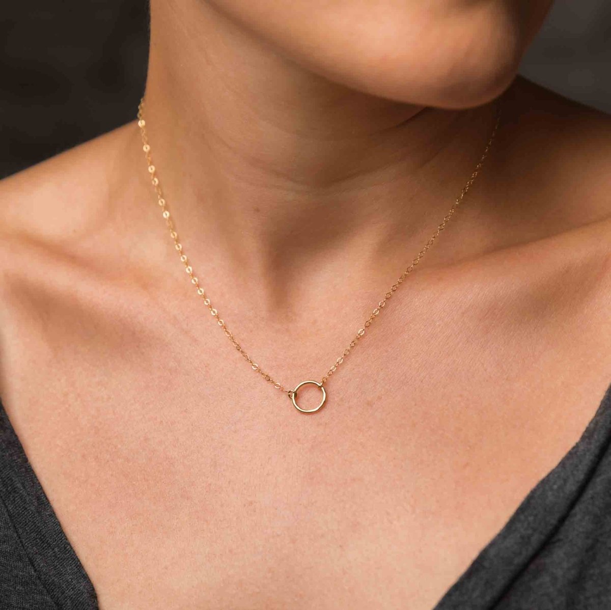 Am Hals des Models hängt eine dünne Goldkette mit einem kleinen Ring-Verbinder in der Mitte