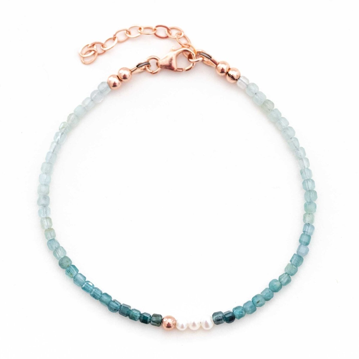 Ein dünnes Armband von Mayam Berlin, bestehend aus kleinen Grandidierit-Perlen mit Farbverlauf und drei Süßwasserperlen in der Mitte liegt auf weißem Hintergrund.