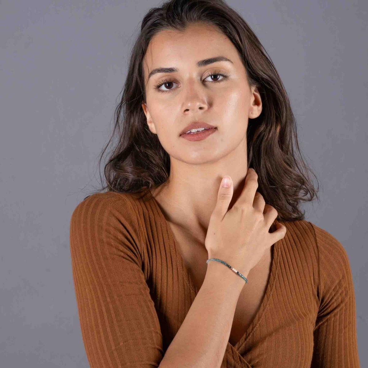 Am Handgelenk des Models hängt ein dünnes Edelstein-Armband, bestehend aus kleinen Grandidierit-Perlen und drei Süßwasserperlen in der Mitte.