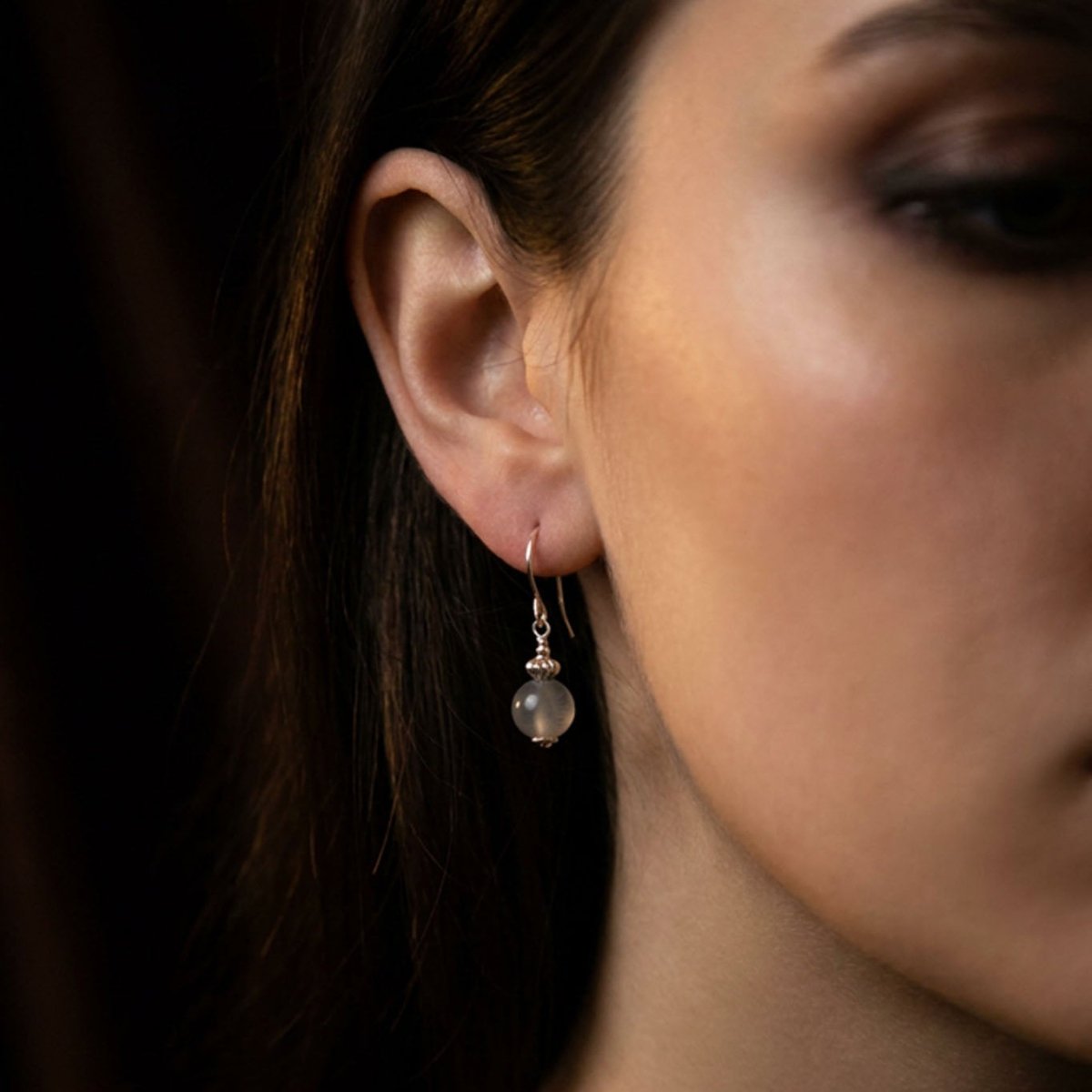 Am Ohr des Models hängt ein Silber-Ohrring mit einer grauen Mondsteinkugel.