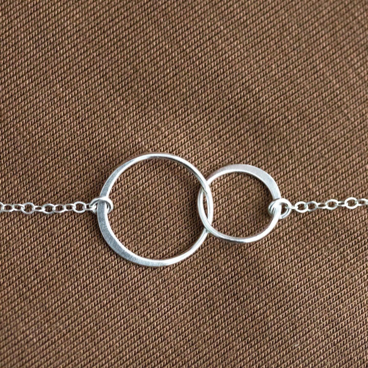 Detailansicht zweier unterschiedlich großer, ineinander verschlungener Silberringe.