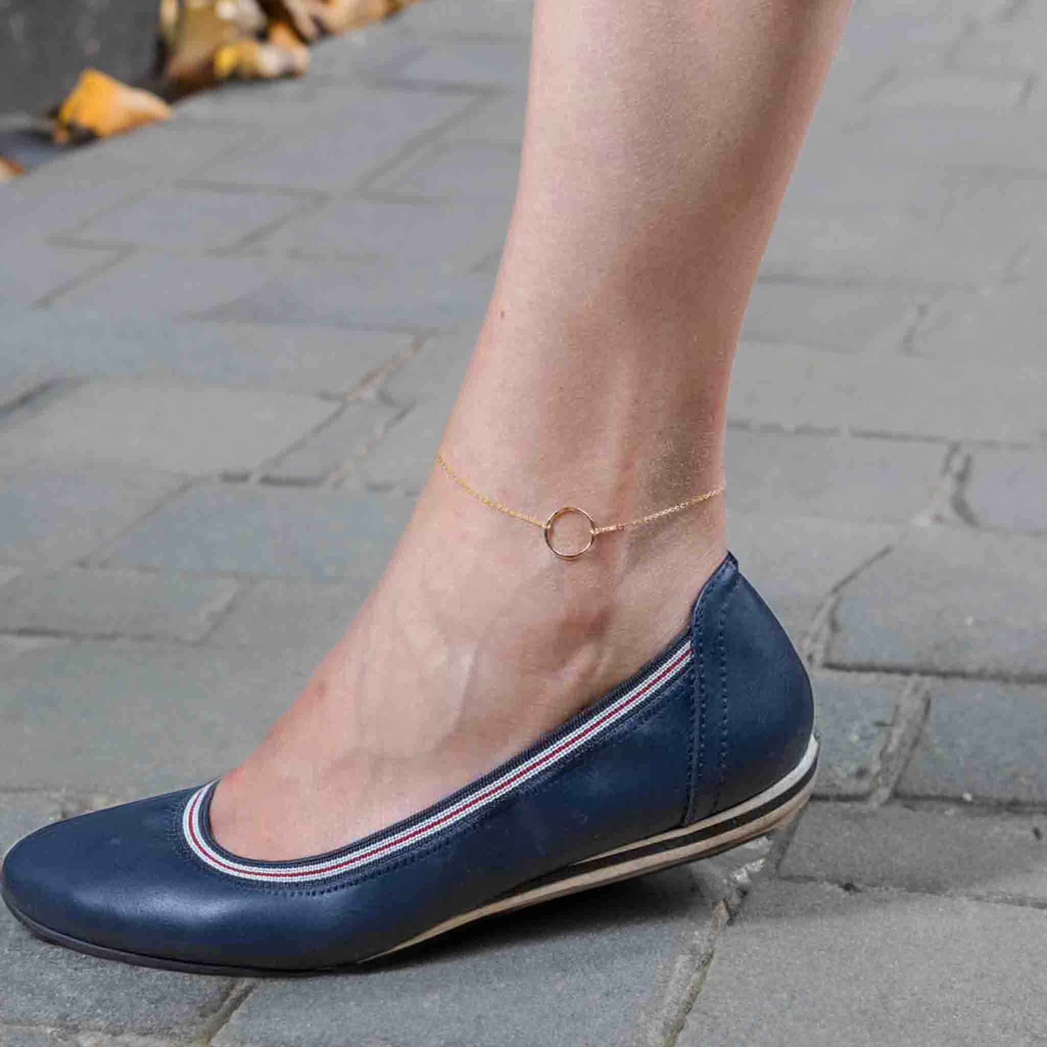 Das Model trägt ein goldenes Fußkettchen mit einem offenen Ring in der Mitte.