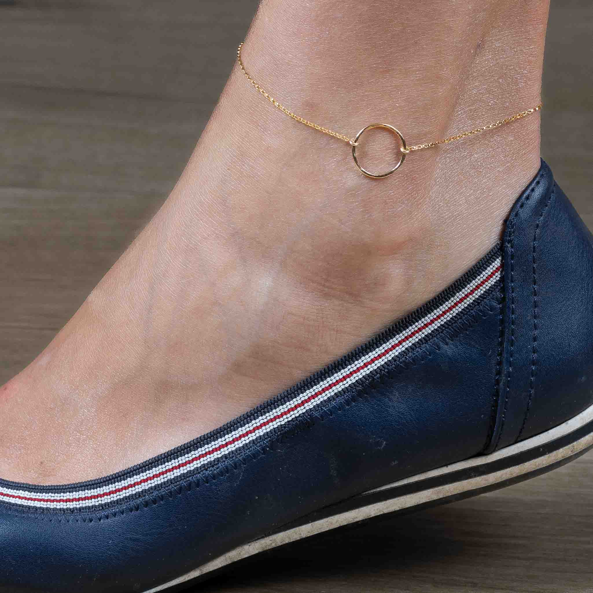 Das Model trägt ein goldenes Fußkettchen mit einem offenen Ring in der Mitte.
