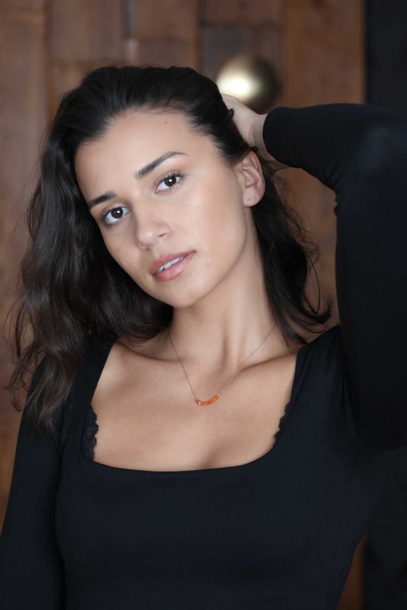 Feine Seidenkette mit orangen Karneol-Rondellen am Hals des Models.