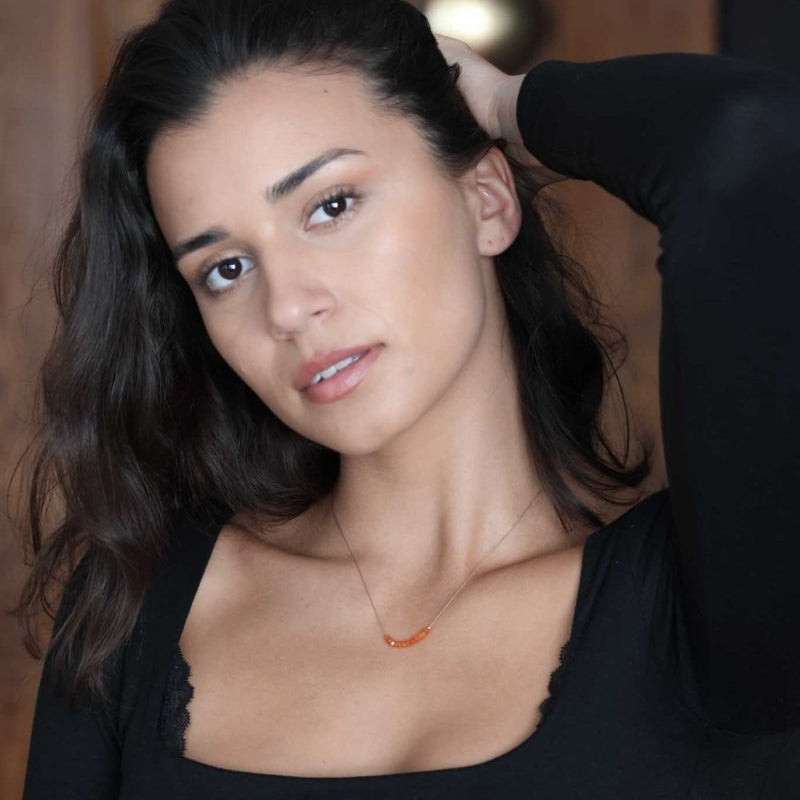 Feine Seidenkette mit orangen Karneol-Rondellen am Hals des Models.