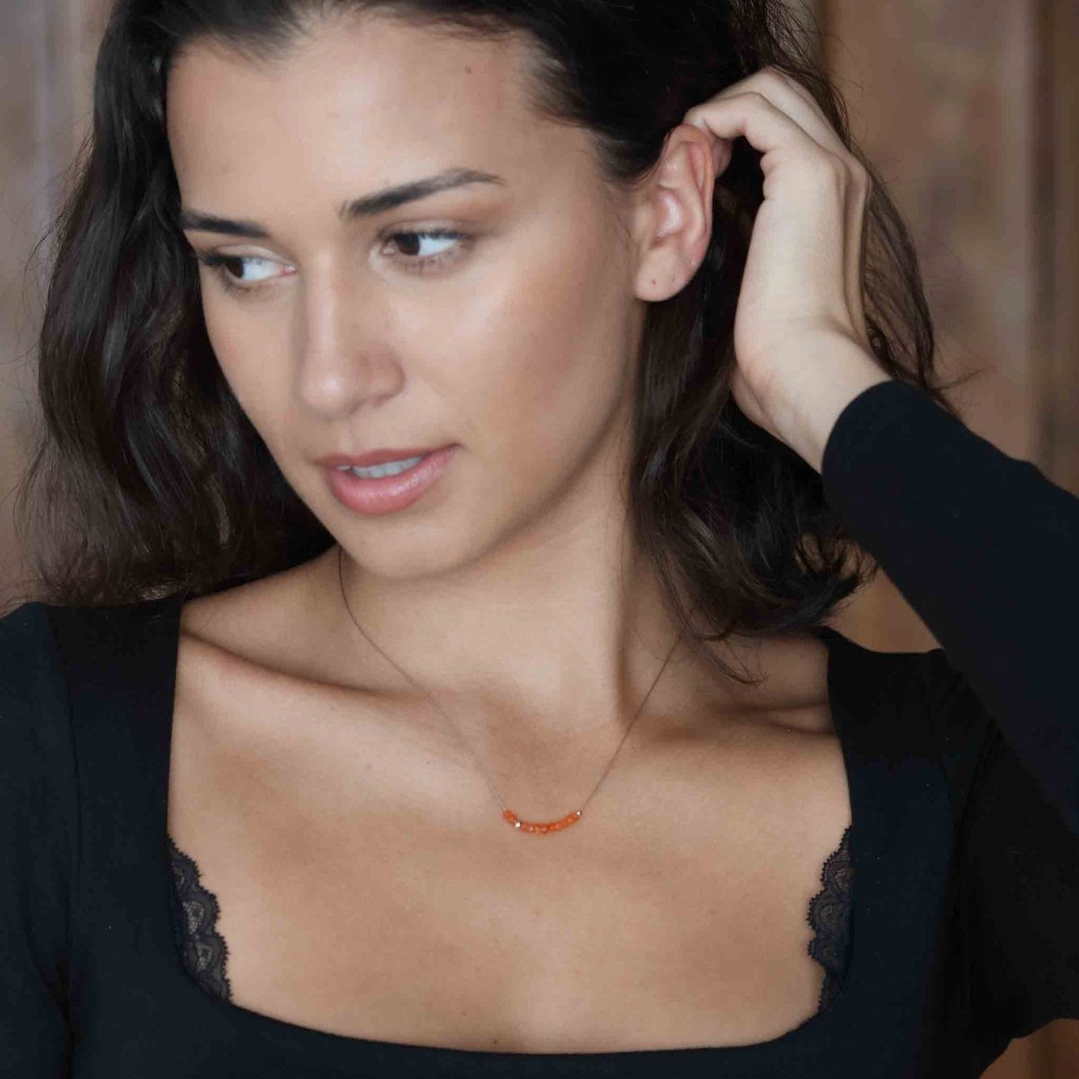 Feine Seidenkette mit orangen Karneol-Rondellen am Hals des Models.