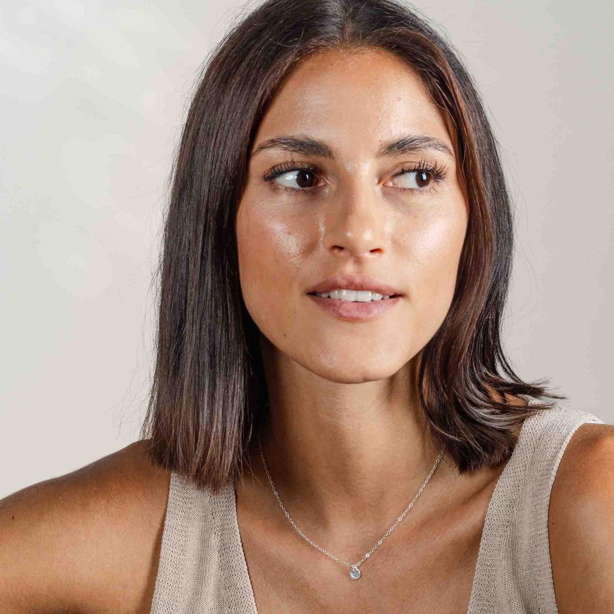 Am Hals des Models hängt eine kurze 925 Silberkette mit einem kleinen, runden Plättchenanhänger, der gehämmert wurde.