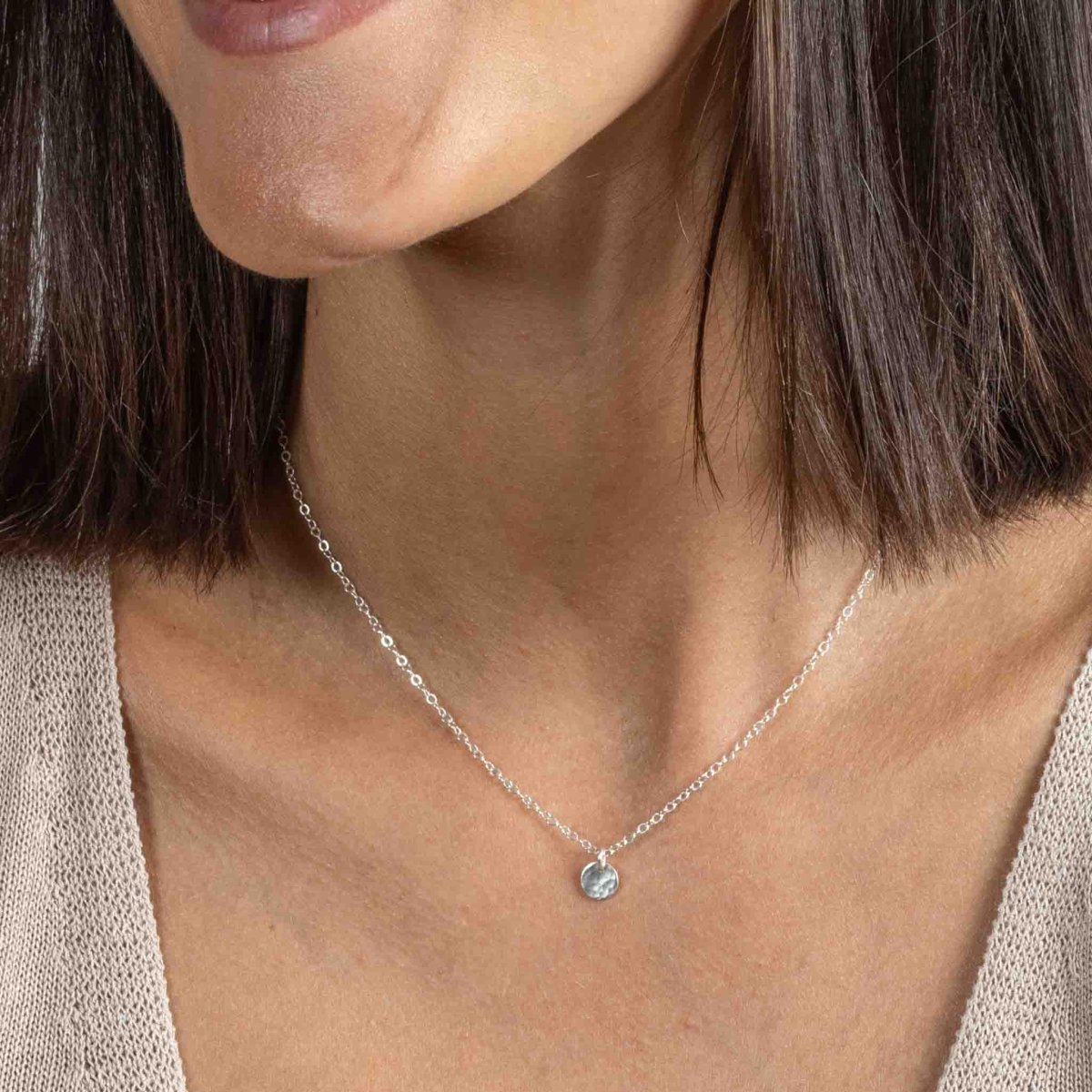 Am Hals des Models hängt eine kurze 925 Silberkette mit einem kleinen, runden Plättchenanhänger, der gehämmert wurde.