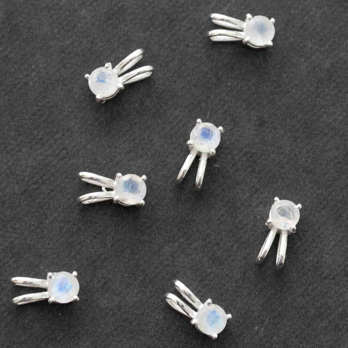 Viele kleine Mondstein Anhänger auf dunklem Hintergrund.