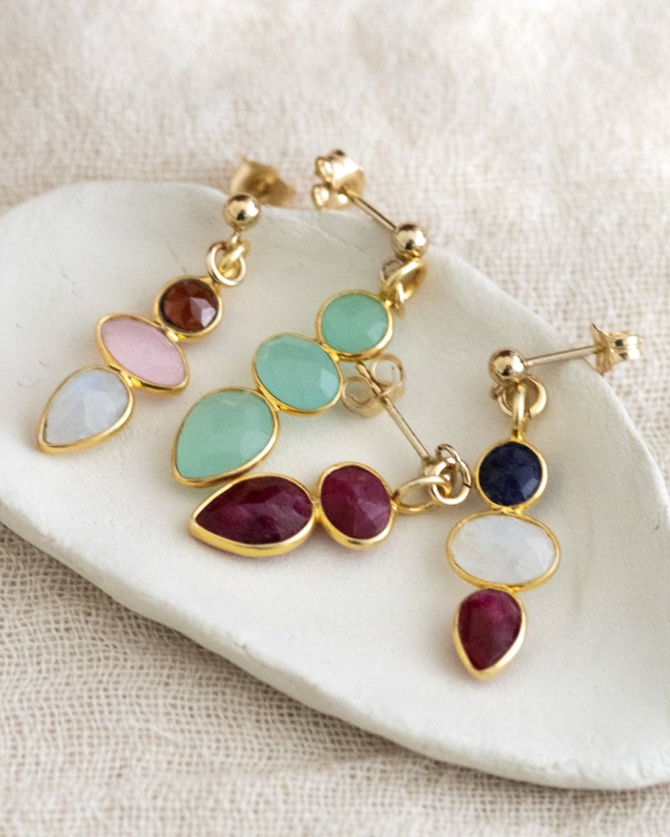 Vier unterschiedliche bunte Ohrringe mit kleinen Edelsteinen liegen in einem weißen Schälchen.