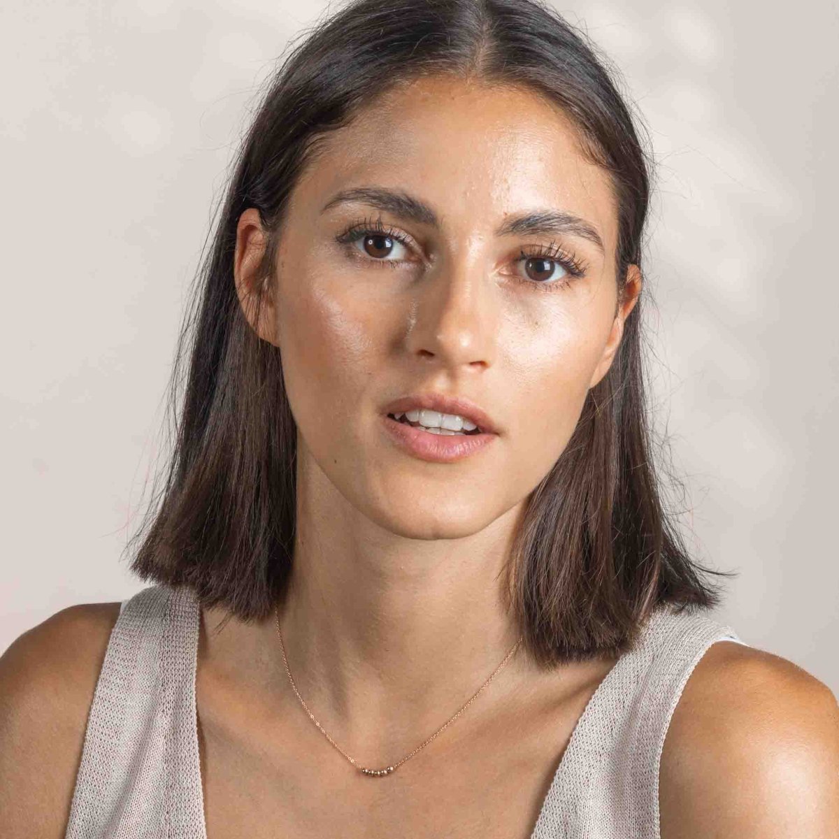 Am Hals des Models hängt eine kurze Roségold-Kette mit fünf aufgezogenen kleinen Rosegold-Perlen in der Mitte.