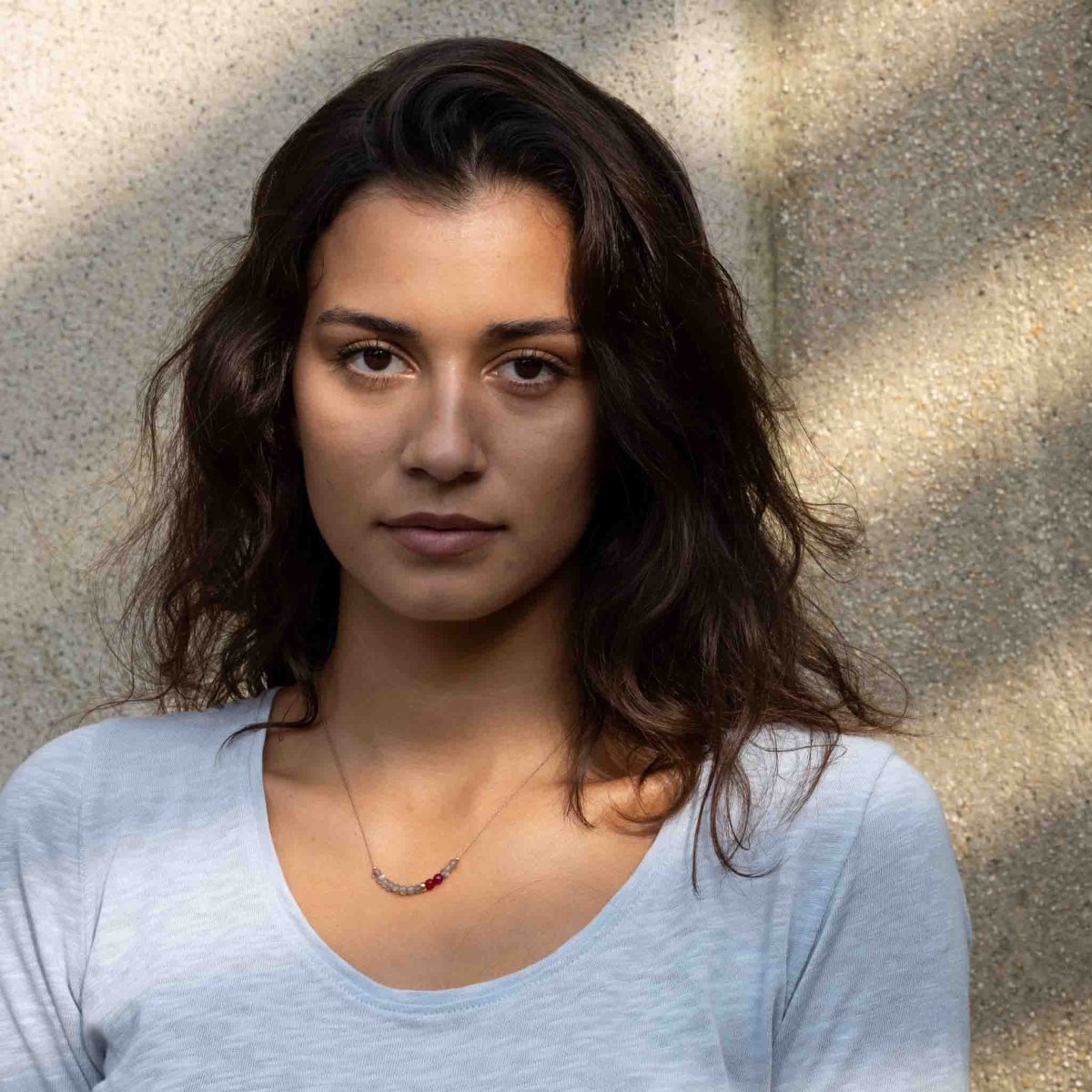 Das Model trägt eine ultra dünne Seidenkette im Farbmix aus grauen Labradorit-Rondellen und himbeerfarbenen Achat-Rondellen.