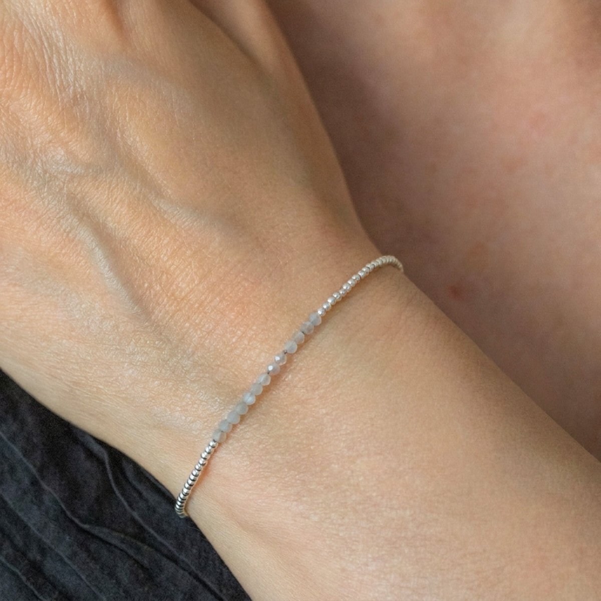 Am Handgelenk des Models hängt ein ultra dünnes Silberarmband mit grauen Mondstein-Perlen in der Mitte.