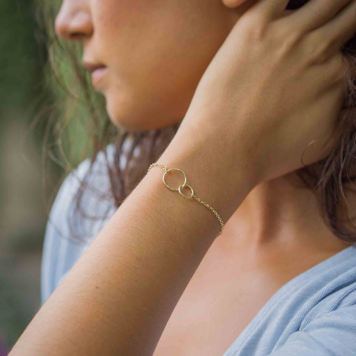 Vergoldetes 925 Silber-Armband mit zwei verschlungenen und gehämmerten Ringen am Handgelenk des Models.