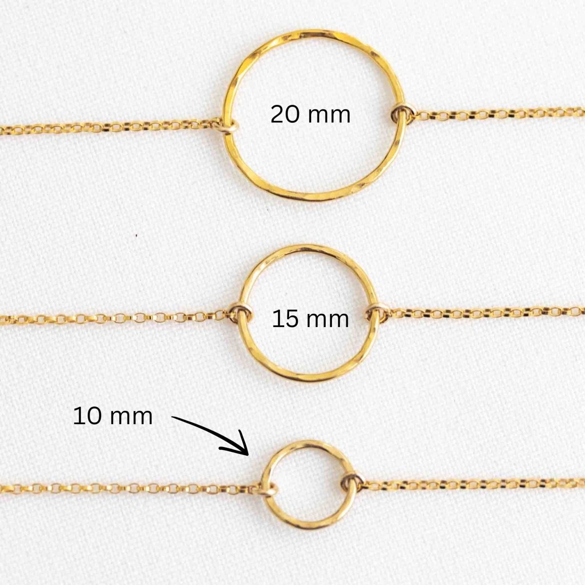 Drei goldene Armbänder auf weißem Hintergrund. Jedes Armband hat einen offenen Ring in der Mitte, einmal in 10 mm, einmal in 15 mm und einmal in 20 mm Größe.
