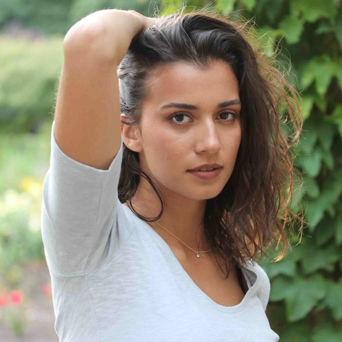 Eine feine Goldkette mit einem winzigen, runden Zirkonia-Anhänger am Hals des Models.
