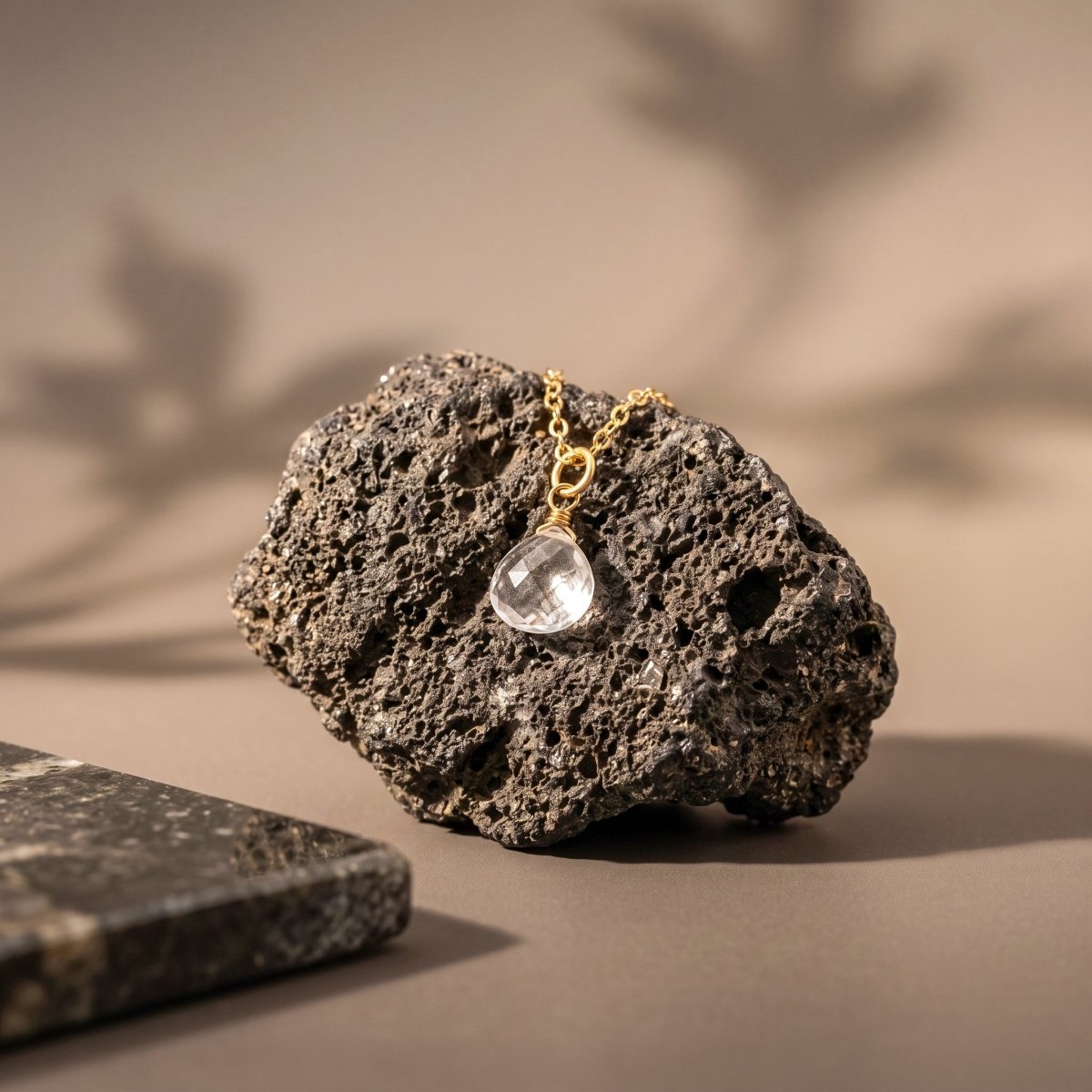 Feine Goldkette mit tropfenförmigen Bergkristall-Anhänger von Deko-Stein hängend.