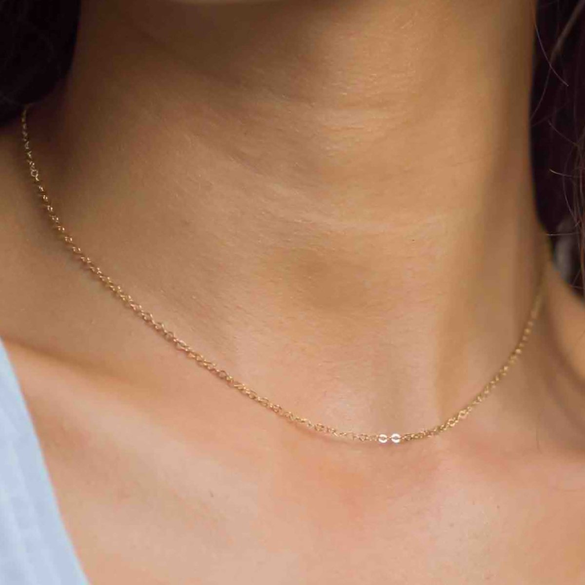 Nahaufnahme einer kurzen, dünnen Ankerkette aus Goldfill am Hals es Models