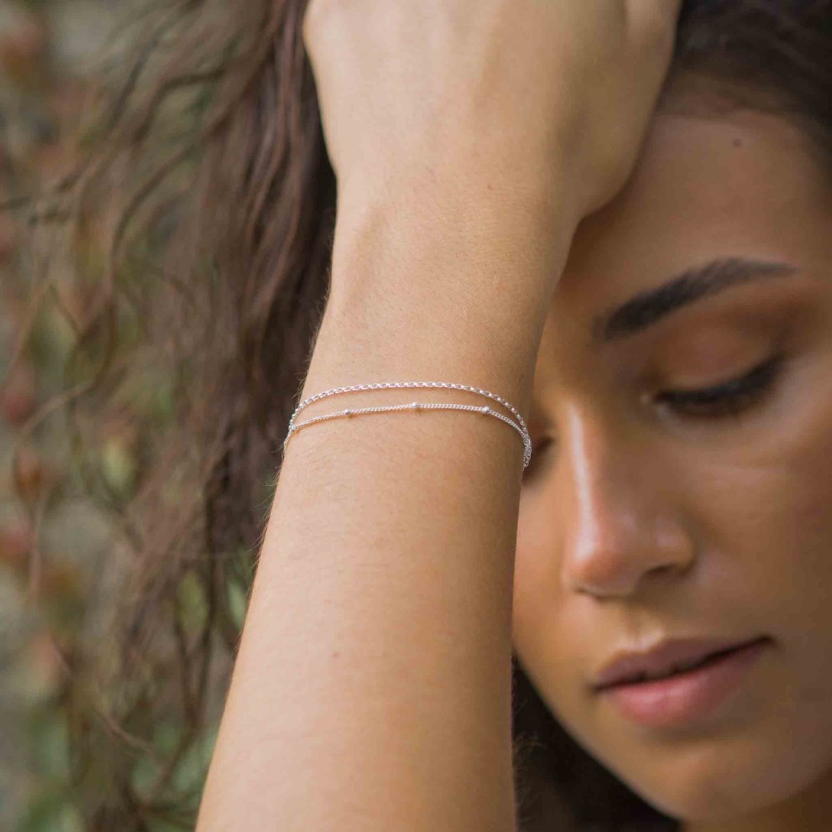 Um das Handgelenk des Models hängt ein doppelreihiges Silber Armband, bestehend aus einer dünnen Erbskette und einer dünnen Satellitenkette.