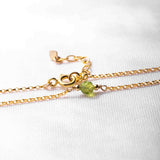 Goldenes Armband mit feiner Kette und einem zentralen, facettierten Peridot-Edelstein, fotografiert auf einem weissen Hintergrund. Produkt von Mayam Berlin