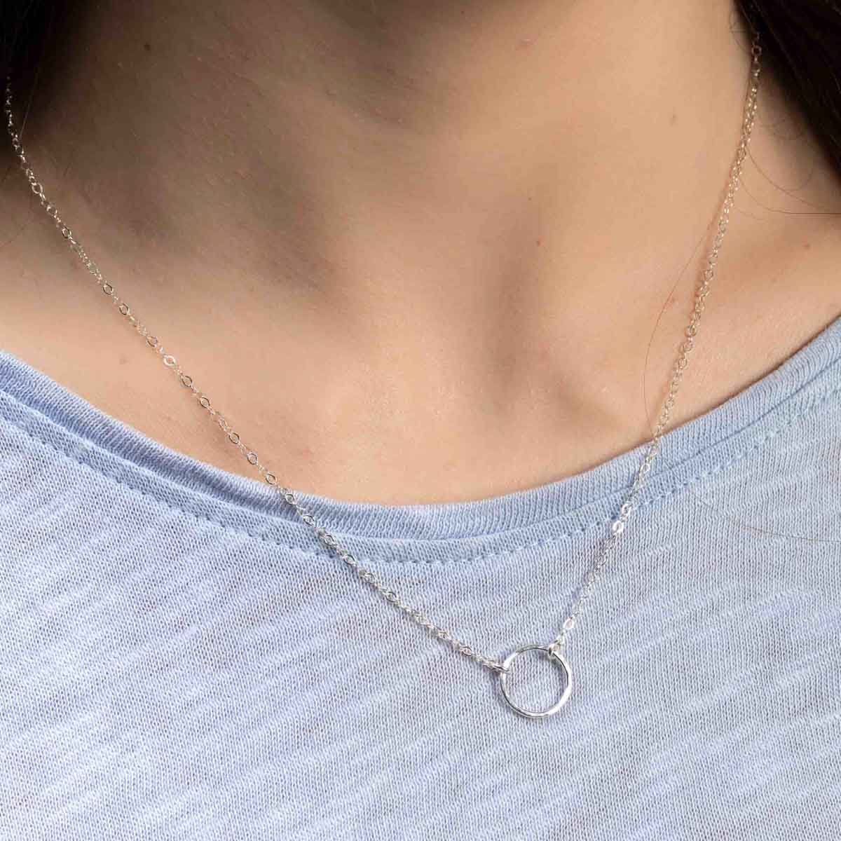 Am Hals des Models hängt eine filigrane Silberkette mit einem offenen Ring in der Mitte.