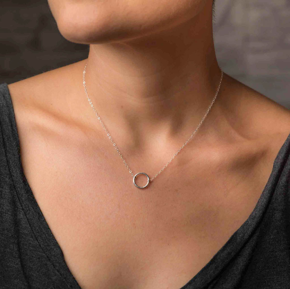 Am Hals des Models hängt eine filigrane Silberkette mit einem offenen Ring in der Mitte.