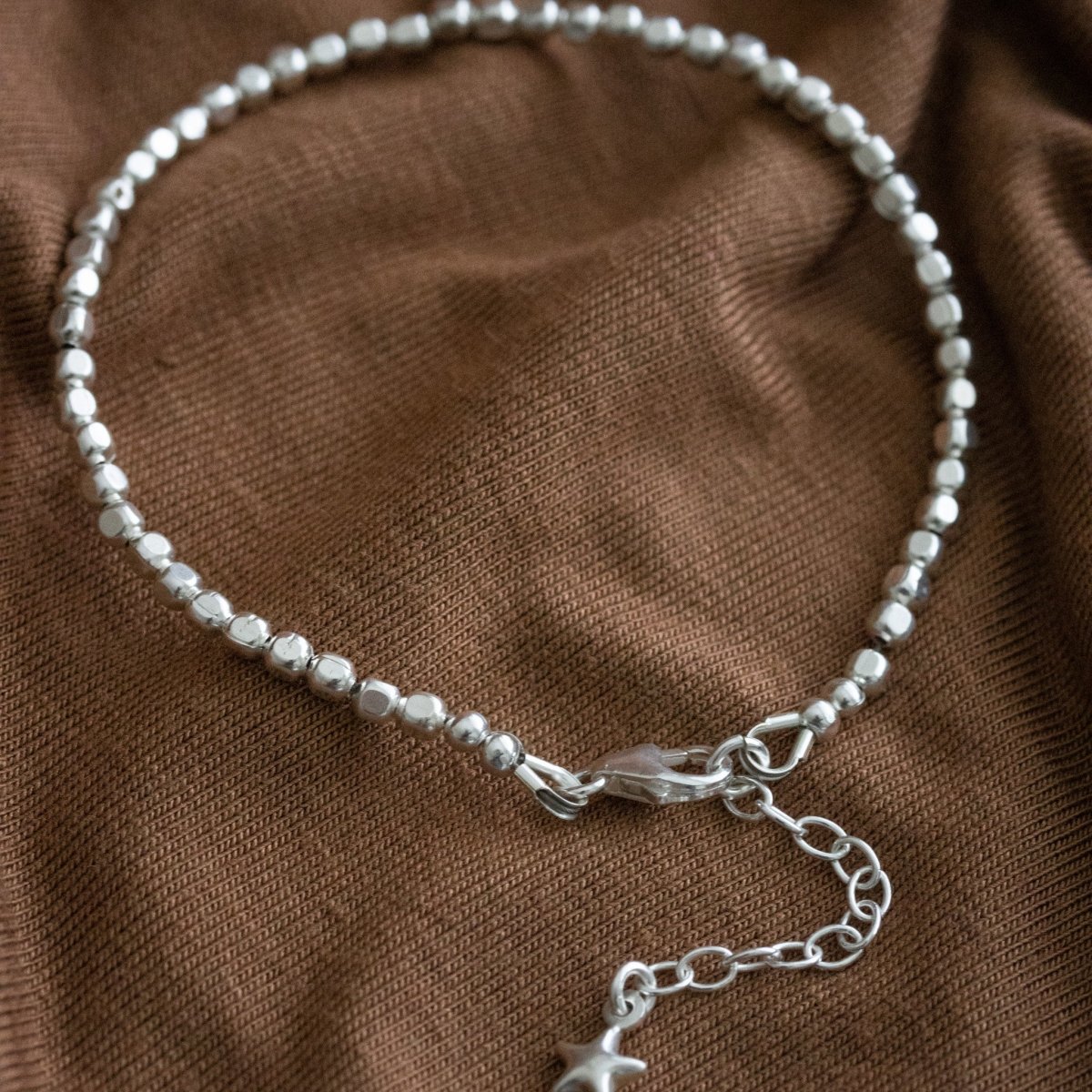 925 Silber Armband aus Mini-Würfeln mit Detail-Ansicht des Karabiner-Verschlusses und Verlängerungskettchen auf Stoff ausgelegt.
