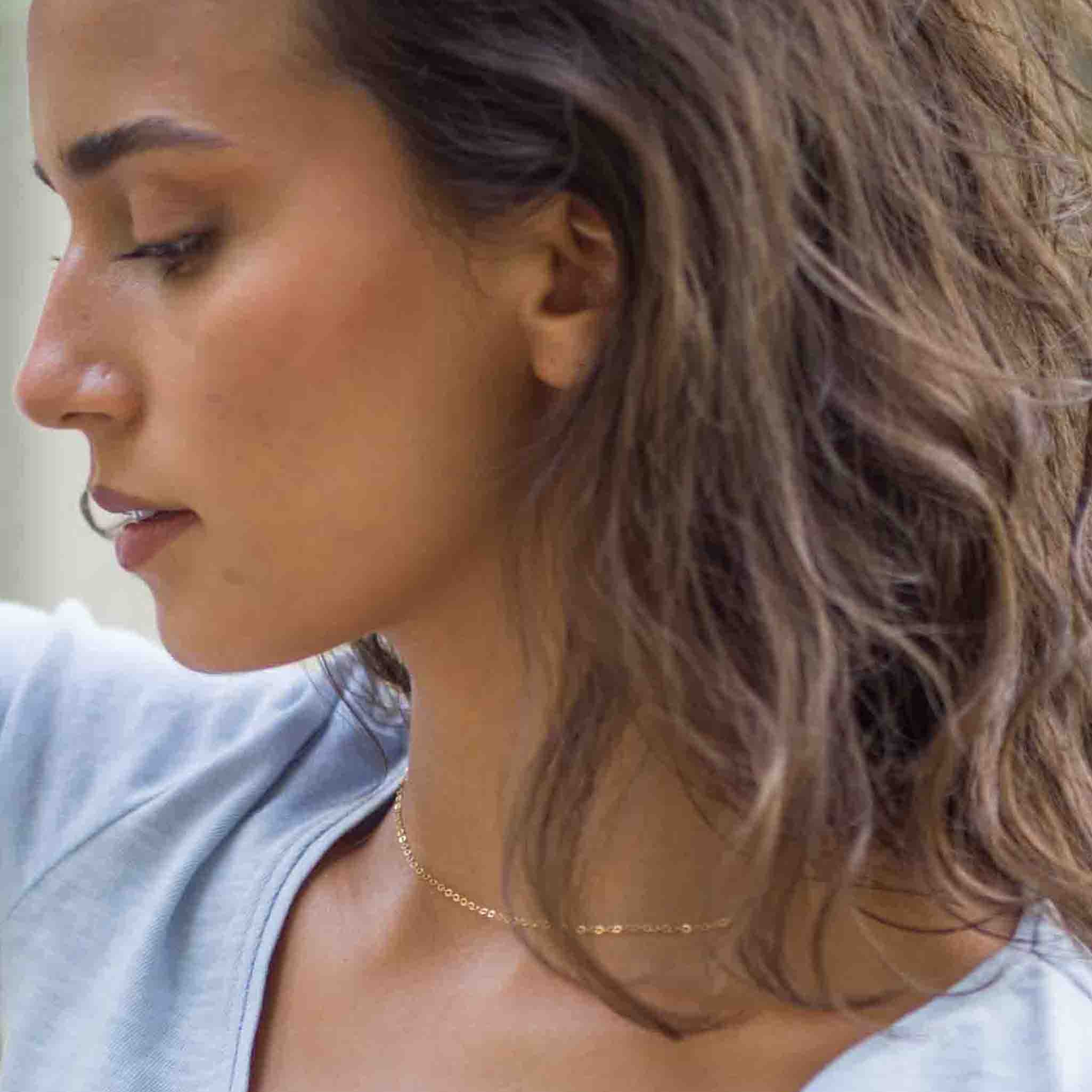 Am Hals des Models hängt eine kurze, feine Goldkette.
