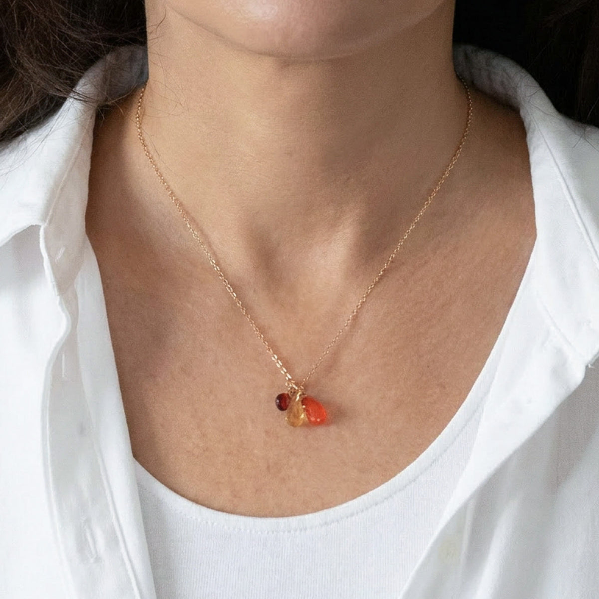 Zierliche Goldkette mit Citrin-, Karneol- und Granat-Anhänger am Hals getragen.
