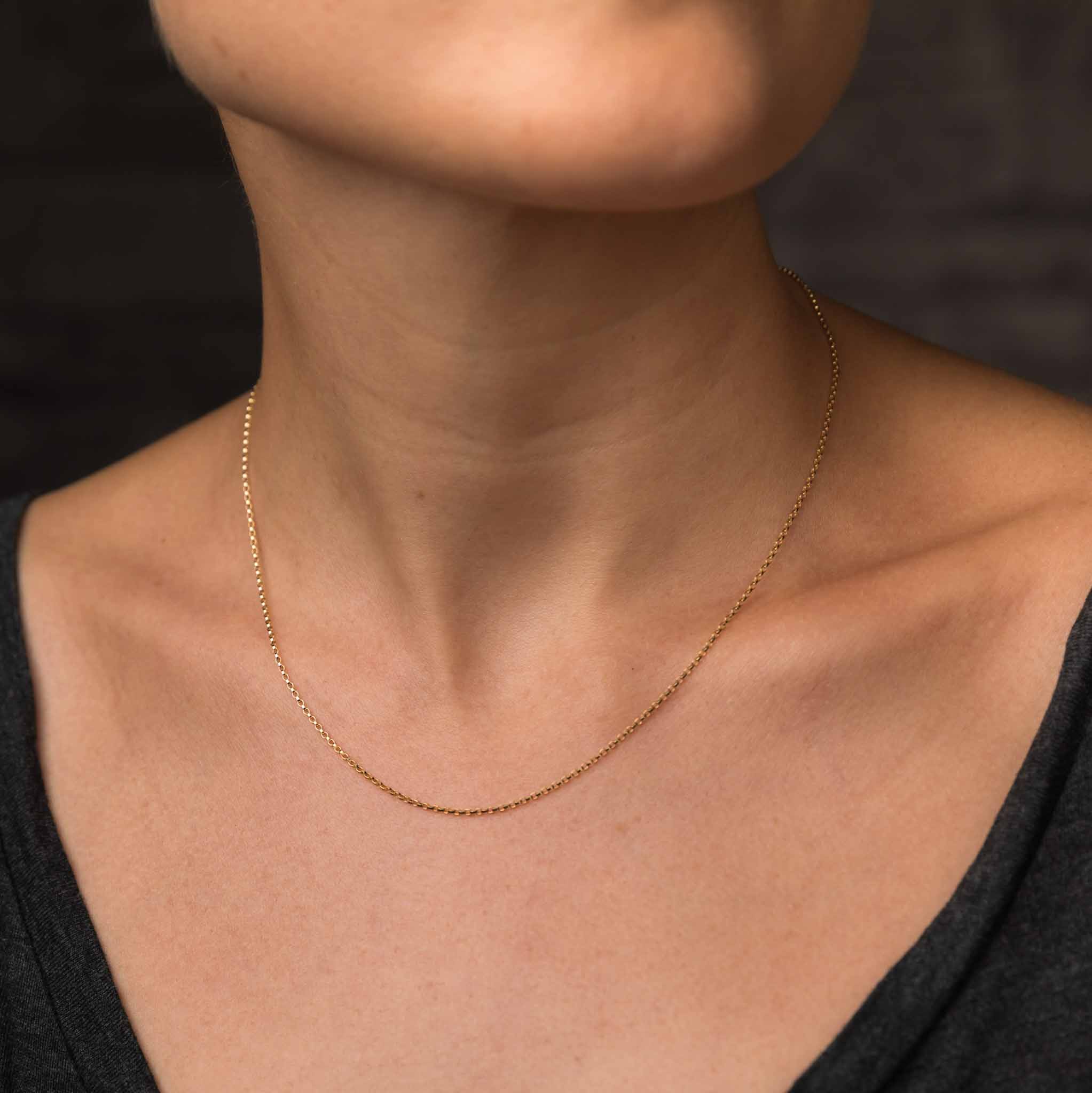 Am Hals des Models hängt eine kurze und zierliche Goldkette aus Goldfill.
