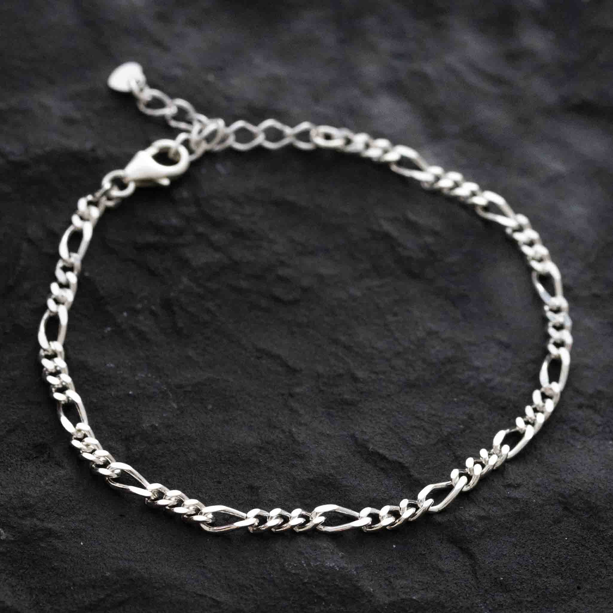 Eine Nahaufnahme eines Mayam Berlin Figaro Armbands aus 925 Silber mit Karabinerverschluss, flach auf einer strukturierten schwarzen Oberfläche liegend.