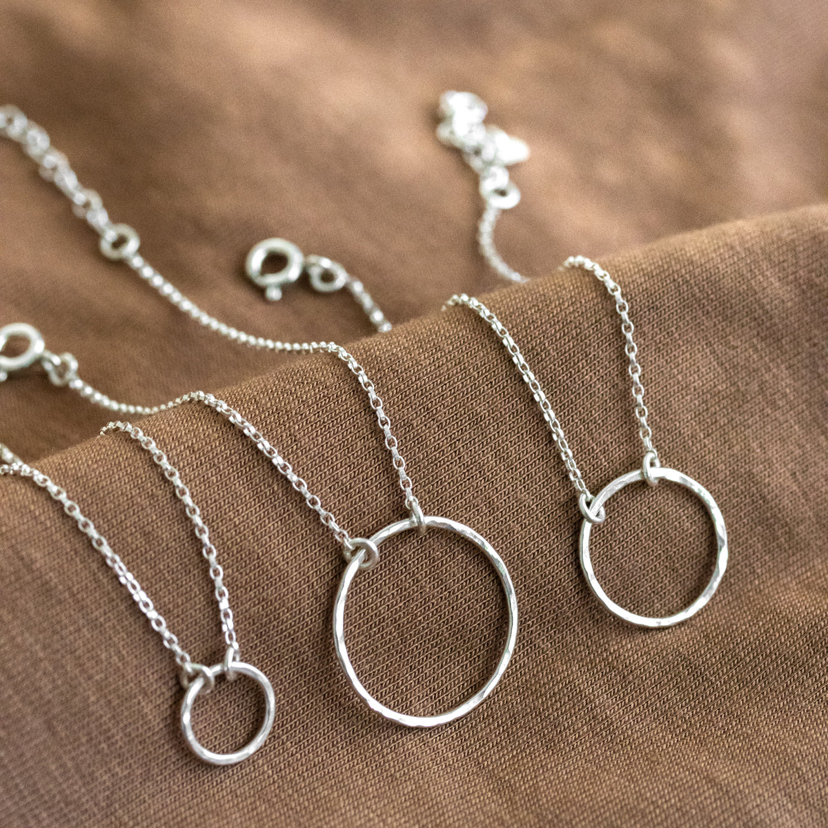 Drei Silberarmbänder mit gehämmerten Kreisen in der Mitte nebeneinander ausgelegt.