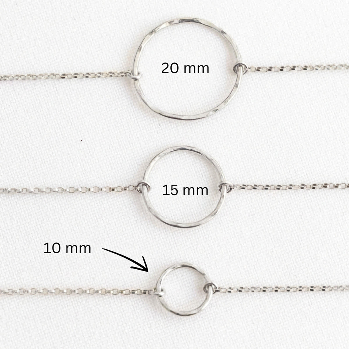 Drei Silberarmbänder mit gehämmerten Kreisen in der Mitte übereinander ausgelegt.