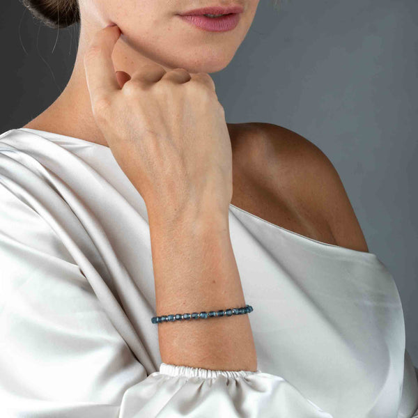 Ein Armband bestehend aus würfelförmigen, blauen Topas-Perlen am Handgelenk des Models