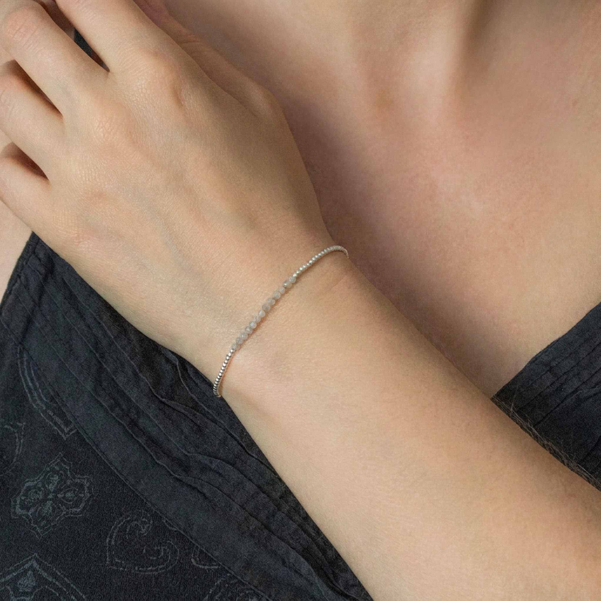 Am Handgelenk des Models hängt ein ultra dünnes Silberarmband mit grauen Mondstein-Perlen in der Mitte.
